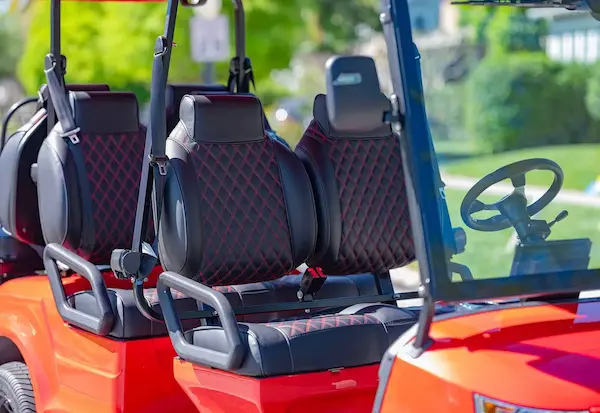 Front and middle bench seating with diamond-stitched black and red cushions in EPIC e60 golf cart